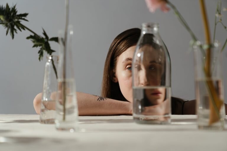 woman in black tank top holding clear glass bottle