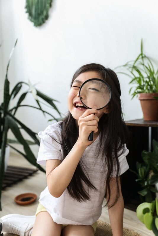 funny asian girl looking through magnifier