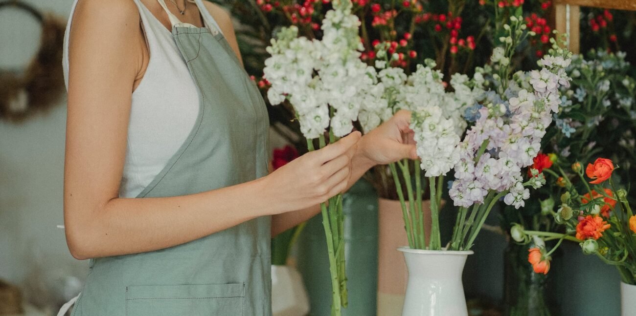 florist in apron arranging flowers in shop