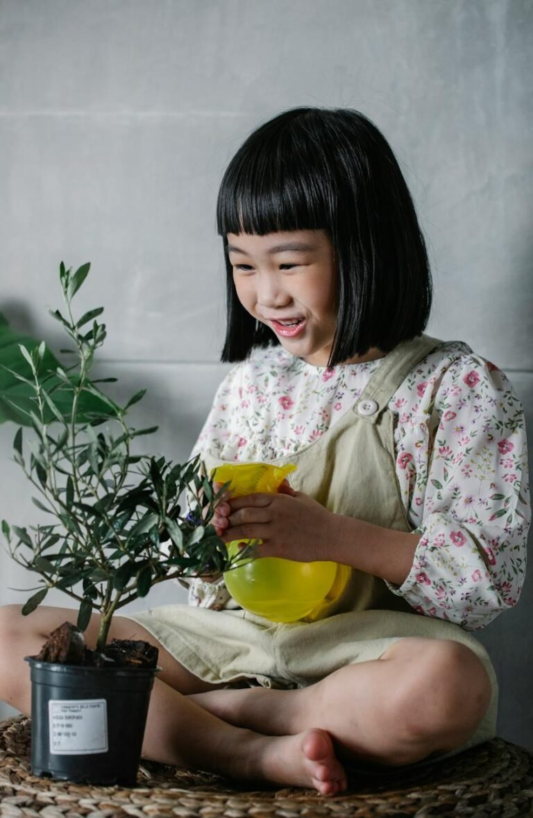 joyful ethnic kid watering potted plant at home