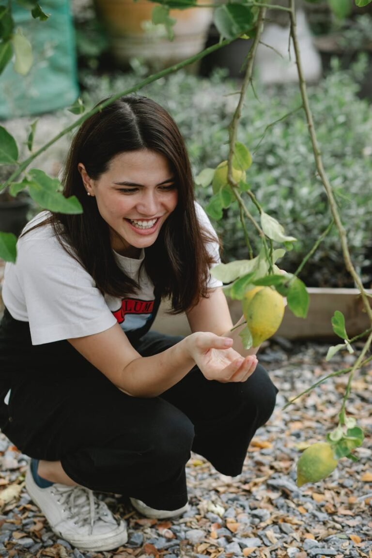 laughing female gardener collecting lemons in garden