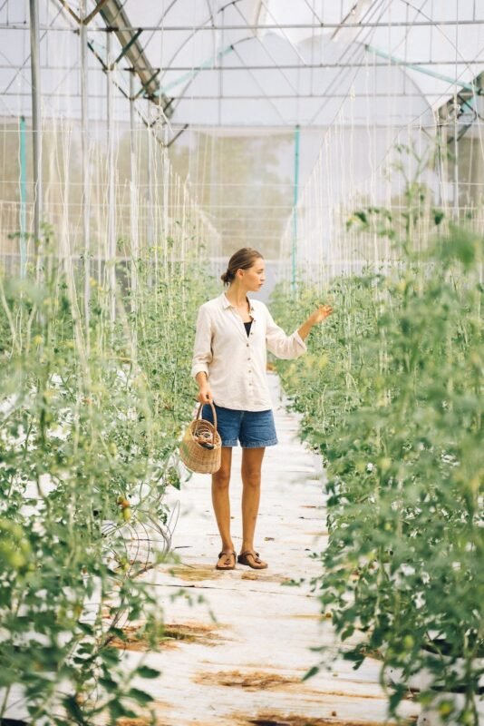 a woman looking at the plants in the greenhouse