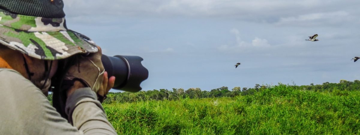 man in gray jacket and black pants taking photo of green grass field during daytime