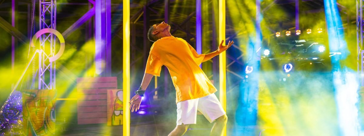 man performing on stage in colorful lights and smoke