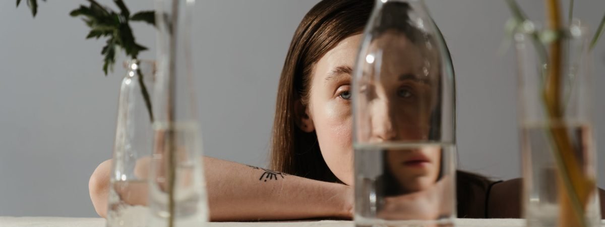 woman in black tank top holding clear glass bottle