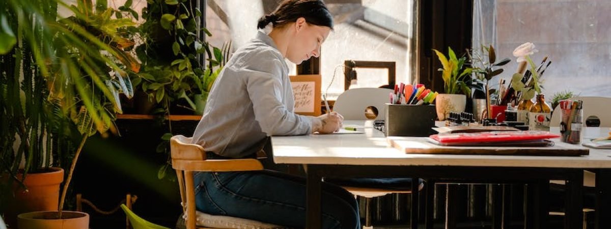 photo of woman sitting by the table while writing