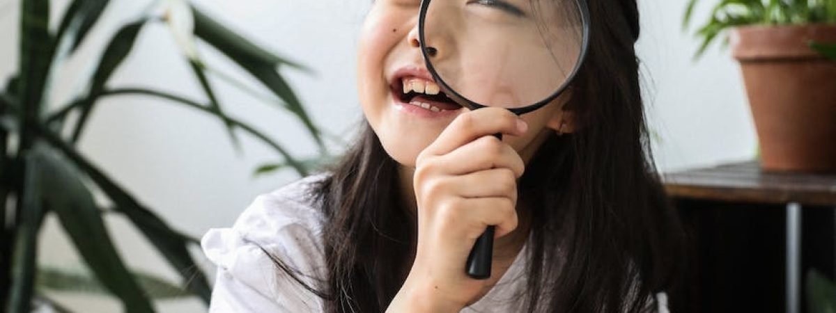 funny asian girl looking through magnifier